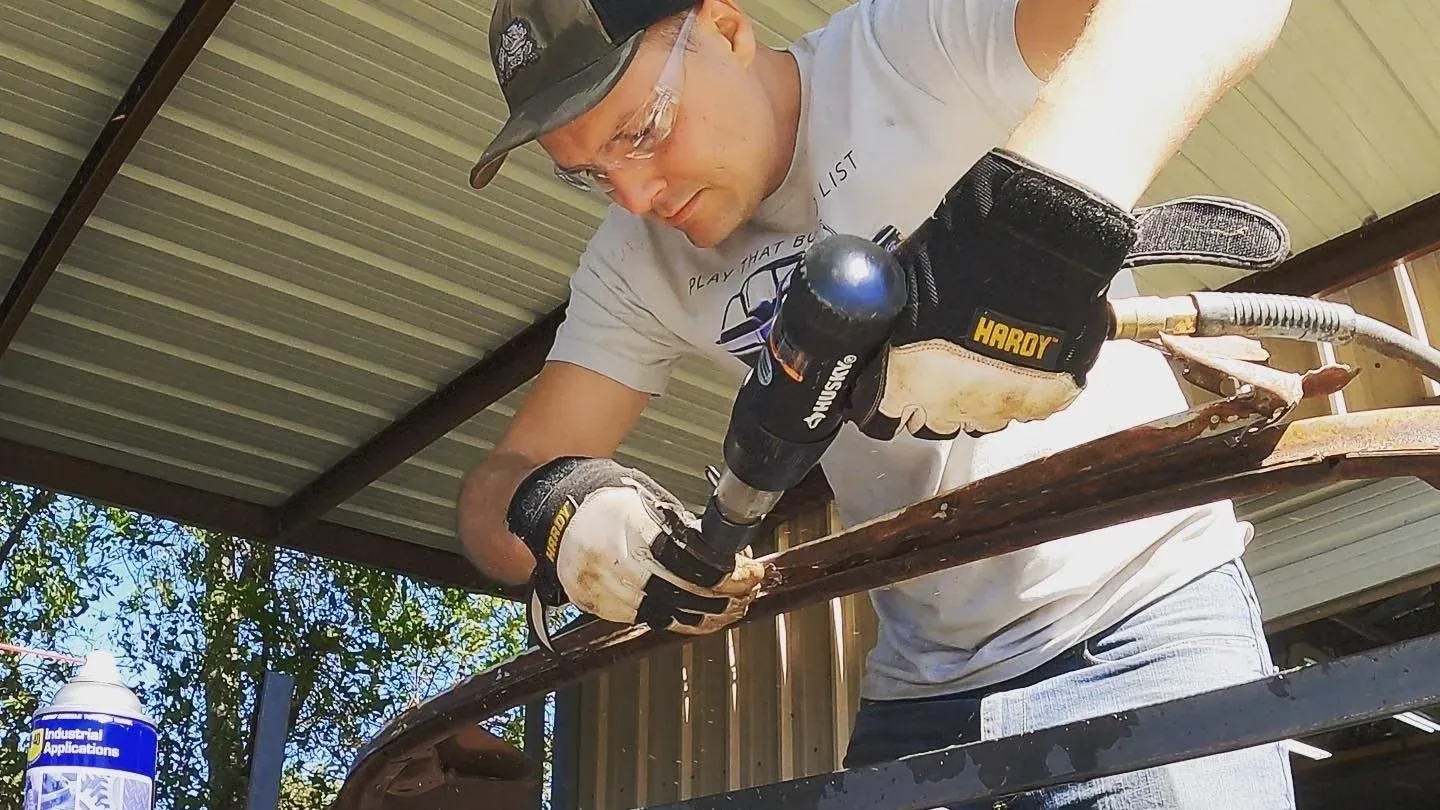 Brian working a heat gun along a Mustang’s window molding under a carport.